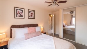 A bedroom with a bed, a ceiling fan, and two framed pictures on the wall. - Shop & Stay at Bicester Village near our 3 Bed Home-  Pass the Keys (Bicester)