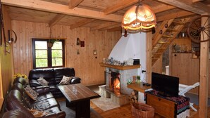 A cozy cabin interior with a fireplace, wooden walls, a leather sofa, and a television. - Holiday Home With Fireplace and Private Garden (gmina Stężyca)