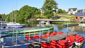 A marina with various boats docked, a wooden pier, and a house in the background. - Holiday Home With Fireplace and Private Garden (gmina Stężyca)