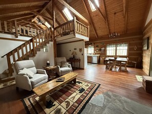 Interior espacioso de una cabaña con escalera de madera, comedor y cocina.