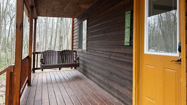 Eine hölzerne Veranda mit einer Bank, einer gelben Tür und einem Fenster mit Rollläden.