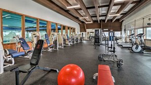 Ein Fitnessstudio mit unterschiedlichen Trainingsgeräten, großen Fenstern und hoher Decke.