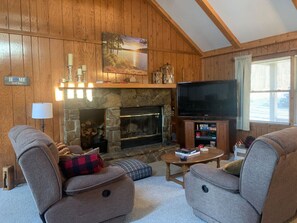 TV connectée, cheminée, livres, écrans d'ordinateur