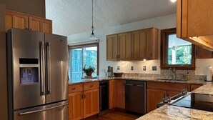 Una cocina moderna con electrodomésticos de acero inoxidable, armarios de madera y encimera de granito.