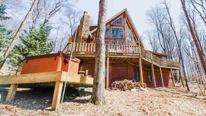 Une cabane en rondins à deux étages, dotée d’une cheminée et d’une terrasse.