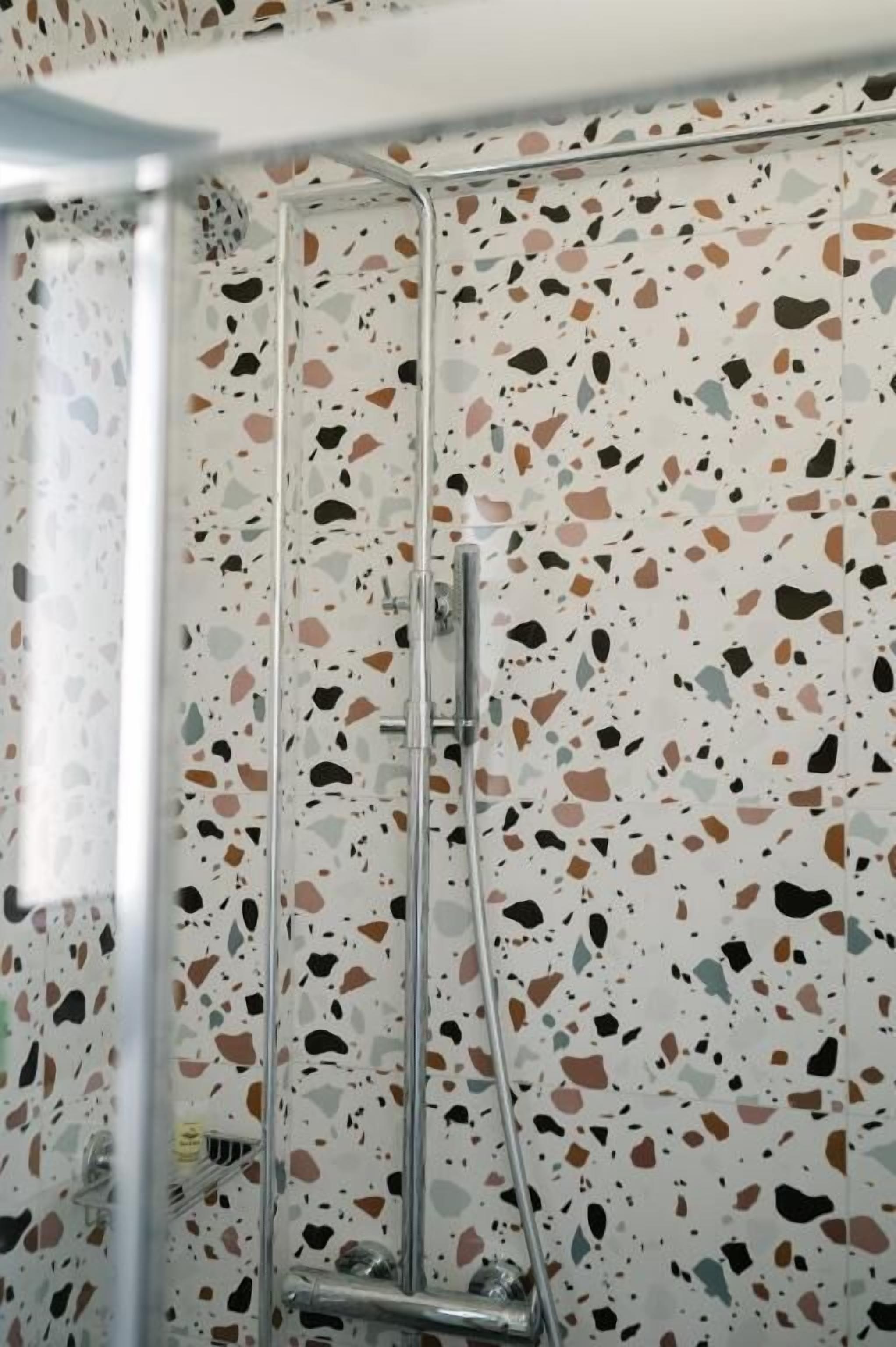 A shower with a terrazzo tile wall.