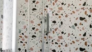 A shower with a terrazzo tile wall.