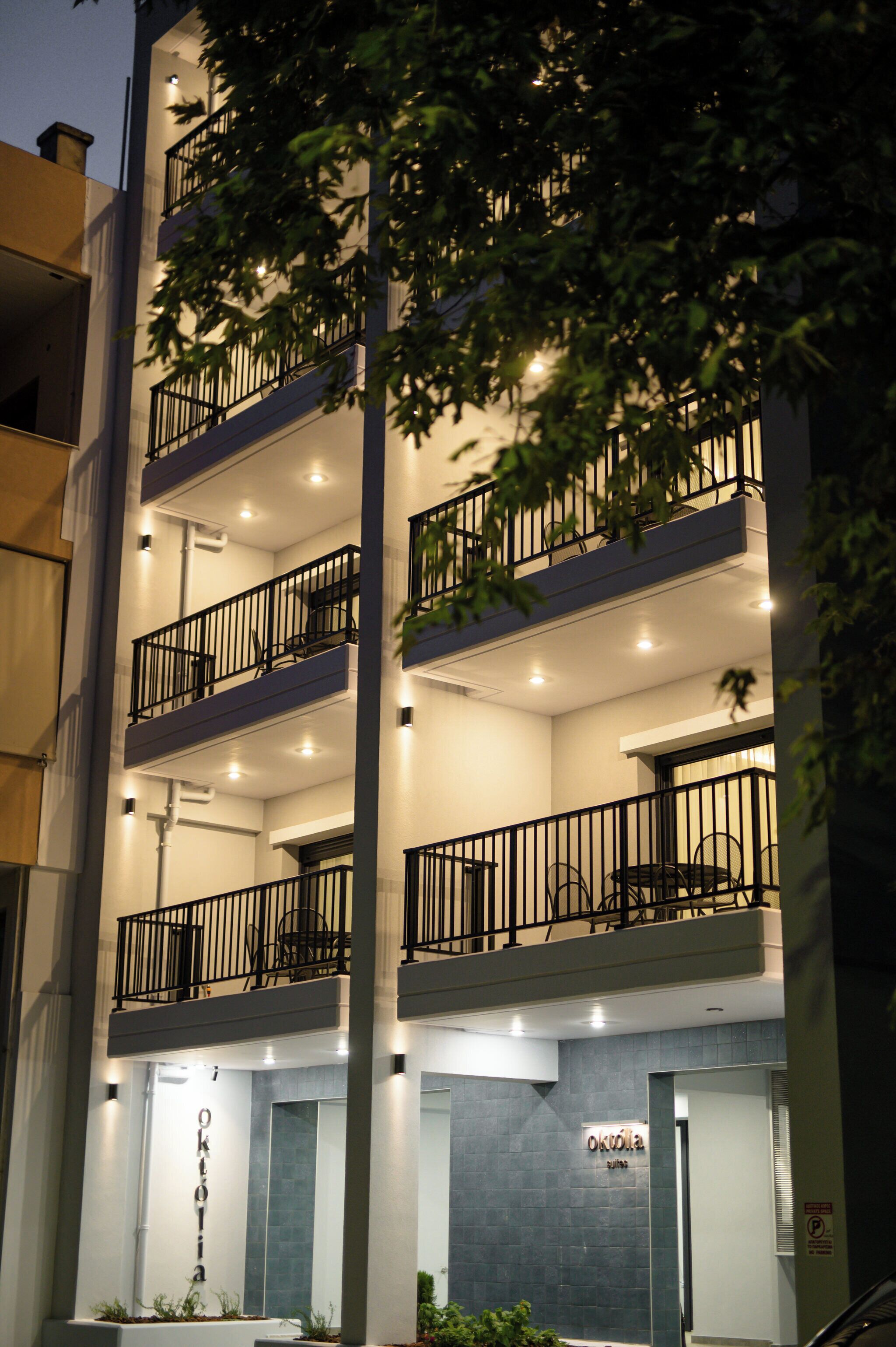 Un edificio de varios pisos con balcones, un letrero que dice “Oktolia” y una entrada bien iluminada.