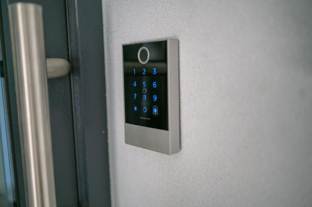 Un teclado numérico fijado a la pared, probablemente para una cerradura, junto a un picaporte metálico.