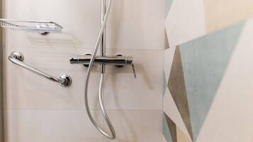 A shower area with chrome fixtures and a tiled wall.