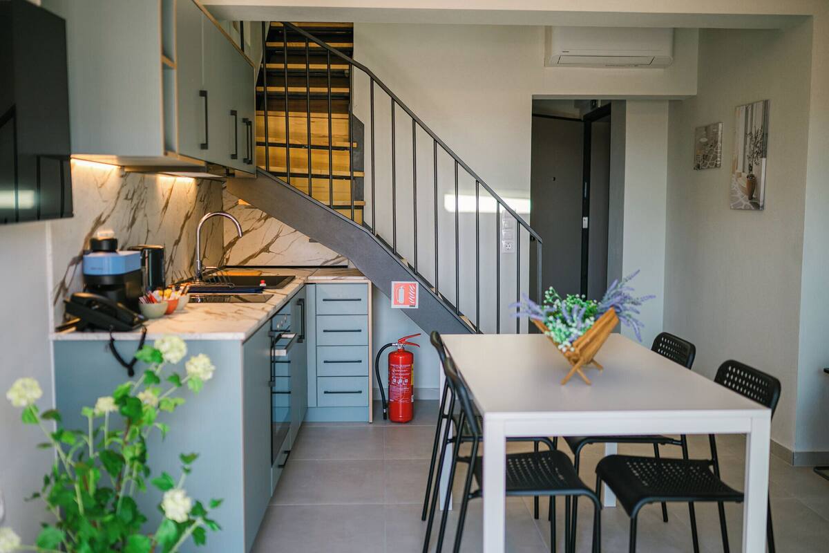 Una cucina moderna con un piano di lavoro in marmo, piano cottura integrato e zona pranzo con tavolo e sedie.