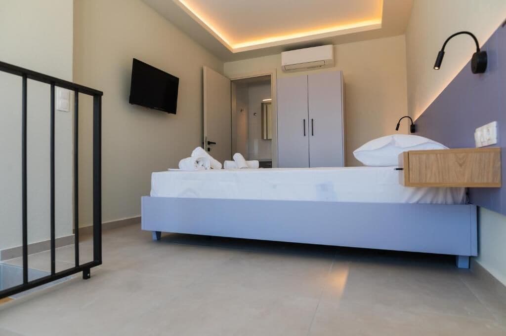Een moderne slaapkamer met een bed, een televisie, een kledingkast en een nachtkastje.
