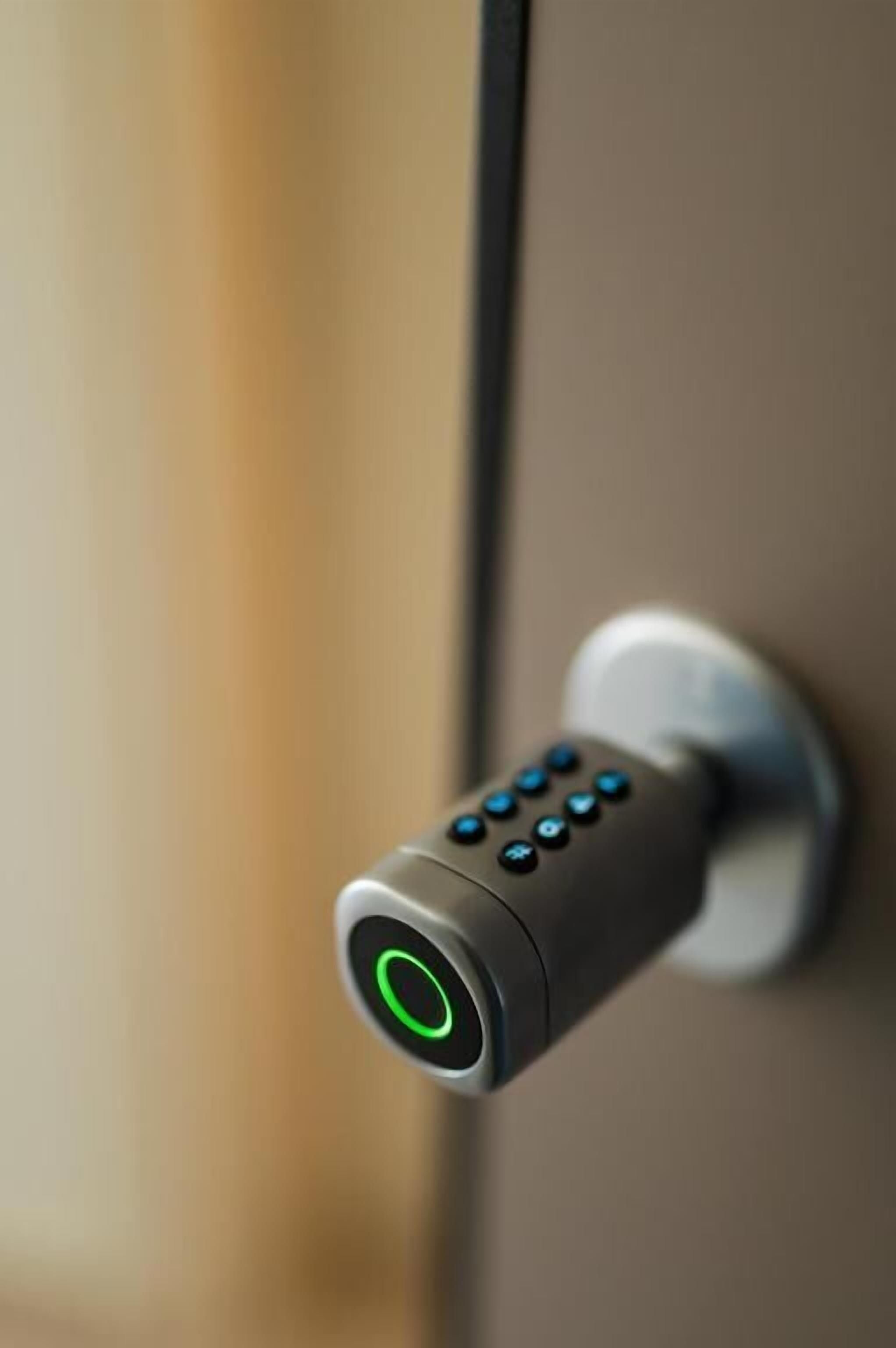 A modern door lock with a numeric keypad and a green indicator light.