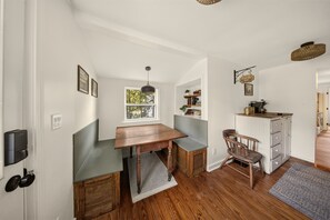 A compact kitchen with a wooden table, a bench, a chair, and a coffee bar.