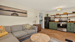 Una sala de estar moderna con un sofá gris, una mesa de centro redonda de madera y un cuadro en la pared.