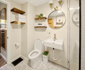 A bathroom with a toilet, sink, and two towel racks.