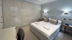 Un dormitorio con una cama grande, un armario, dos mesitas de noche y una silla.