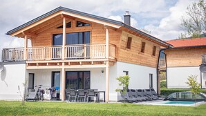 A two-story wooden house with a balcony, a swimming pool, and a covered outdoor seating area. - Inzell Chalets With Private Pool (Inzell)