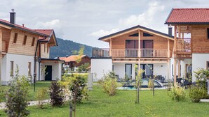 A row of wooden houses with balconies, a swimming pool, and a mountainous backdrop. - Inzell Chalets With Private Pool (Inzell)