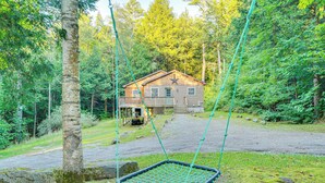 A rustic cabin with a swing set in a forested area. - Cabin w/ Beach Access in Brant Lake: Dogs Welcome! (Brant Lake)