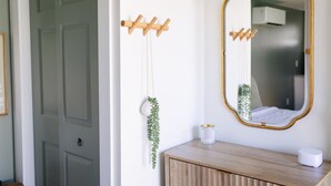 Un bagno con un armadietto in legno, uno specchio con cornice dorata e una pianta pensile.