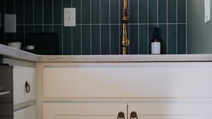 Una cucina con mobili bianchi, una cappa in acciaio inossidabile e una finestra sopra il lavello.