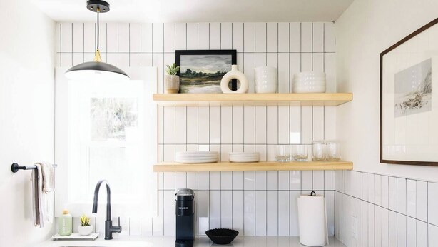 Une cuisine moderne avec des carreaux blancs, une machine à café noire et des étagères en bois.