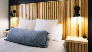 Un lit avec du linge de lit blanc et deux oreillers, encadré de deux têtes de lit en bois dotées de lattes verticales.