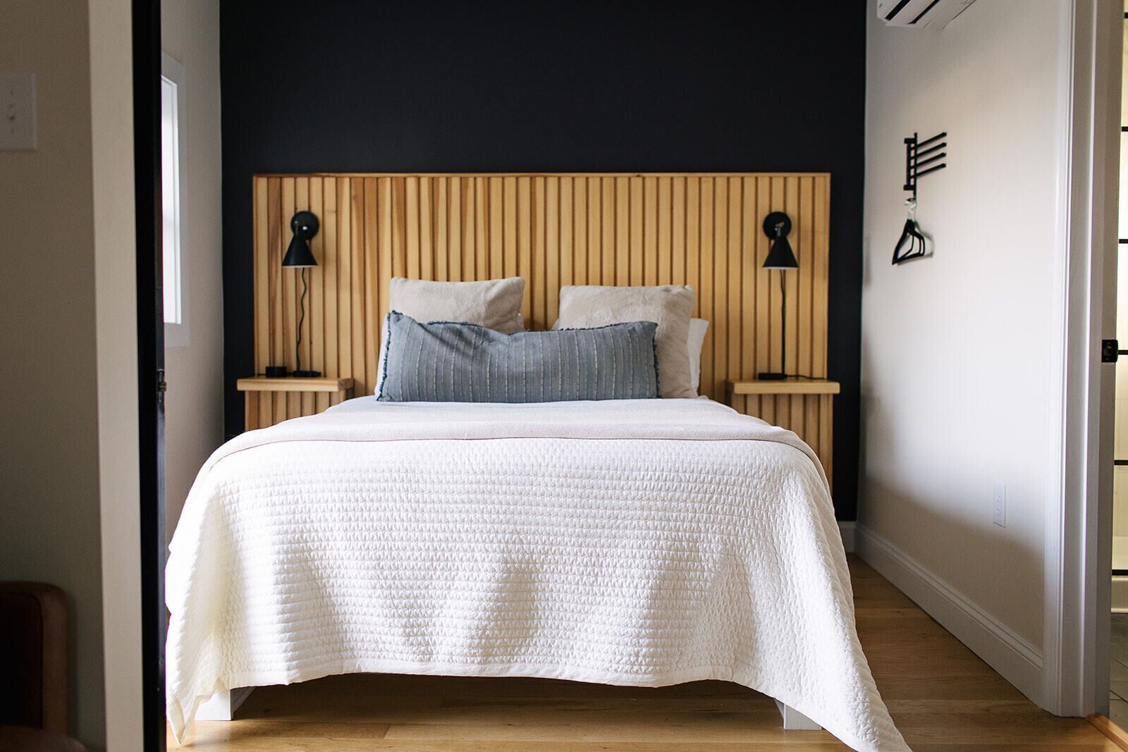 A bedroom with a bed, two bedside tables, and a wooden headboard.
