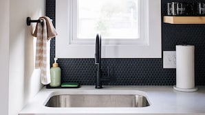 A kitchen with a window, a sink, a towel rack, and a soap dispenser.