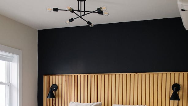 A bedroom with a wooden slat headboard, a white bedspread, and two bedside lamps.