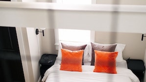 A bedroom with a bed, two nightstands, a bedside table, a lamp, and a window. - Tiny Home with Loft, WI-FI + Free Parking! (Chambersburg)
