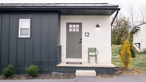 A single-story house with a dark exterior, a white door, and the number 12 on the wall.