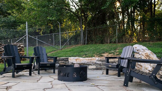 A fire pit area with Adirondack chairs and a stone fire pit labeled "Mane & Co."