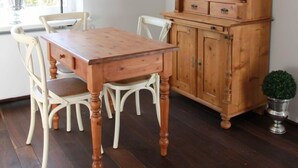 Comedor con mesa y sillas de madera, un aparador de madera con puertas de cristal y una lámpara colgante.