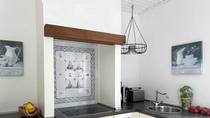 Una cocina moderna con armarios blancos, encimera negra y salpicadero con motivos náuticos.