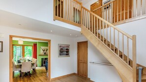 A spacious room with a wooden staircase, a dining area with a table set for four, and a view of the outdoors through a window. - A magnificent property in a secluded position in Evanton. (Evanton, near Dingwall)