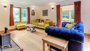 A living room with two sofas, a wooden table, and a small cabinet. - A magnificent property in a secluded position in Evanton. (Evanton, near Dingwall)