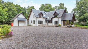 A two-story building with a gravel driveway and a small garden area. - A magnificent property in a secluded position in Evanton. (Evanton, near Dingwall)