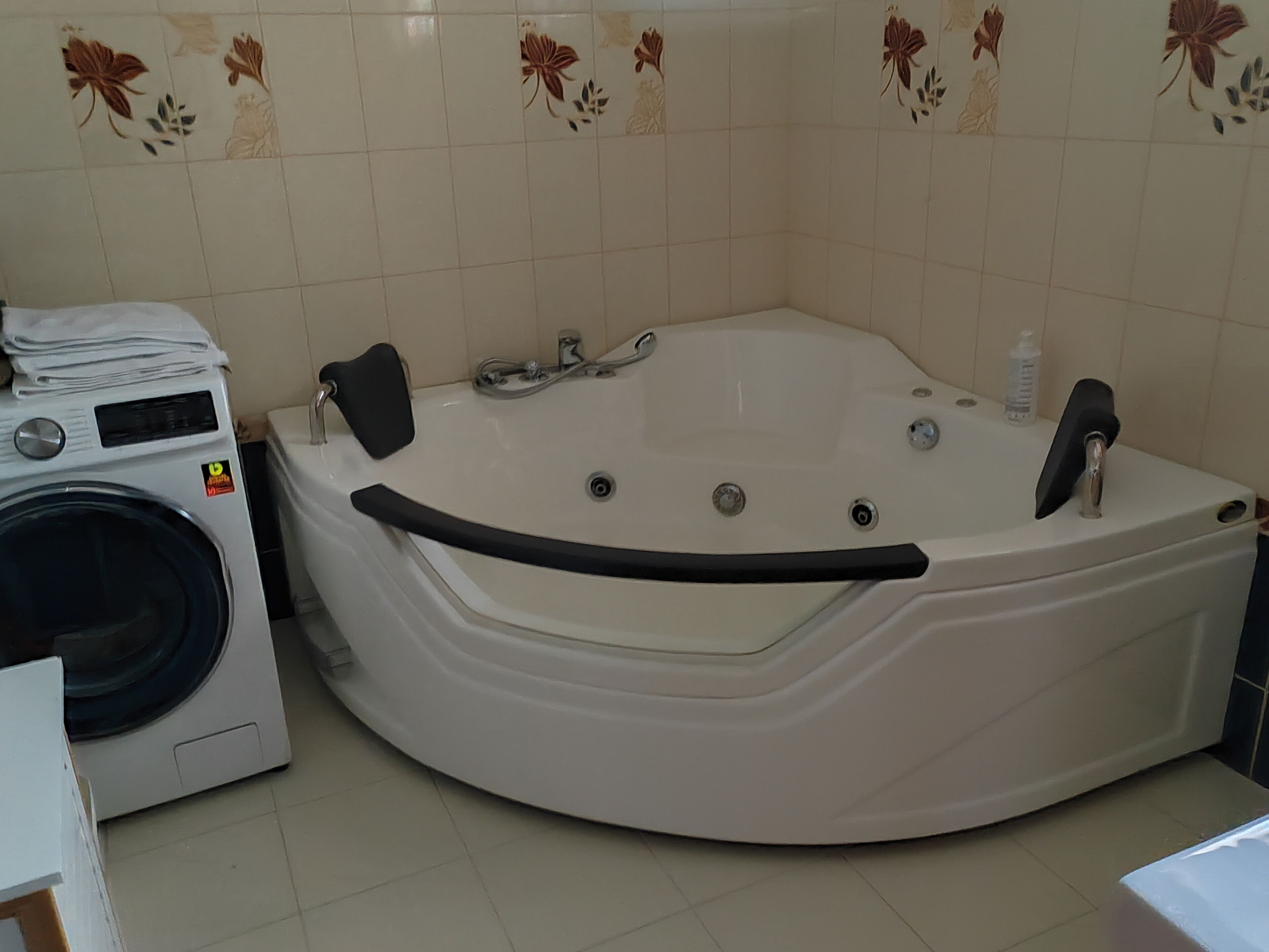 Ett badrum med ett stort badkar, en tvättmaskin och en toalett.