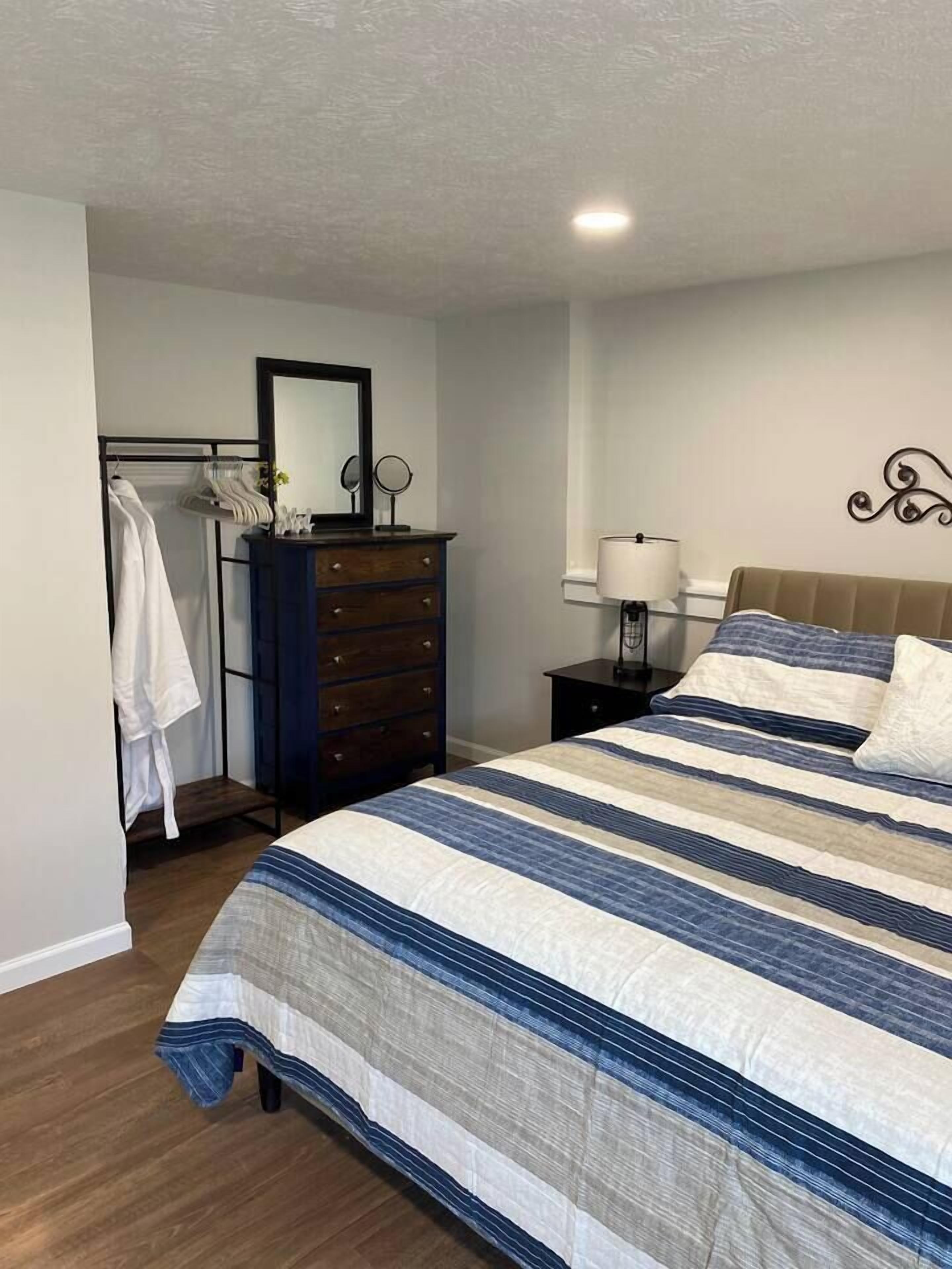 A bedroom with a bed, dresser, mirror, and a lamp.