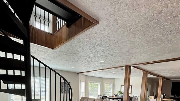 A spacious living area with a wooden staircase, a sectional sofa, and a large window providing natural light. - Pristine Home Perfect for Family Bay Views Luxe Chef’s Kitchen Ludington Park (Escanaba)