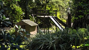 Una terraza de madera con un cobertizo pequeño y un farol en un jardín exuberante.