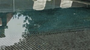 Piscina con dos sillones blancos y una valla al fondo.