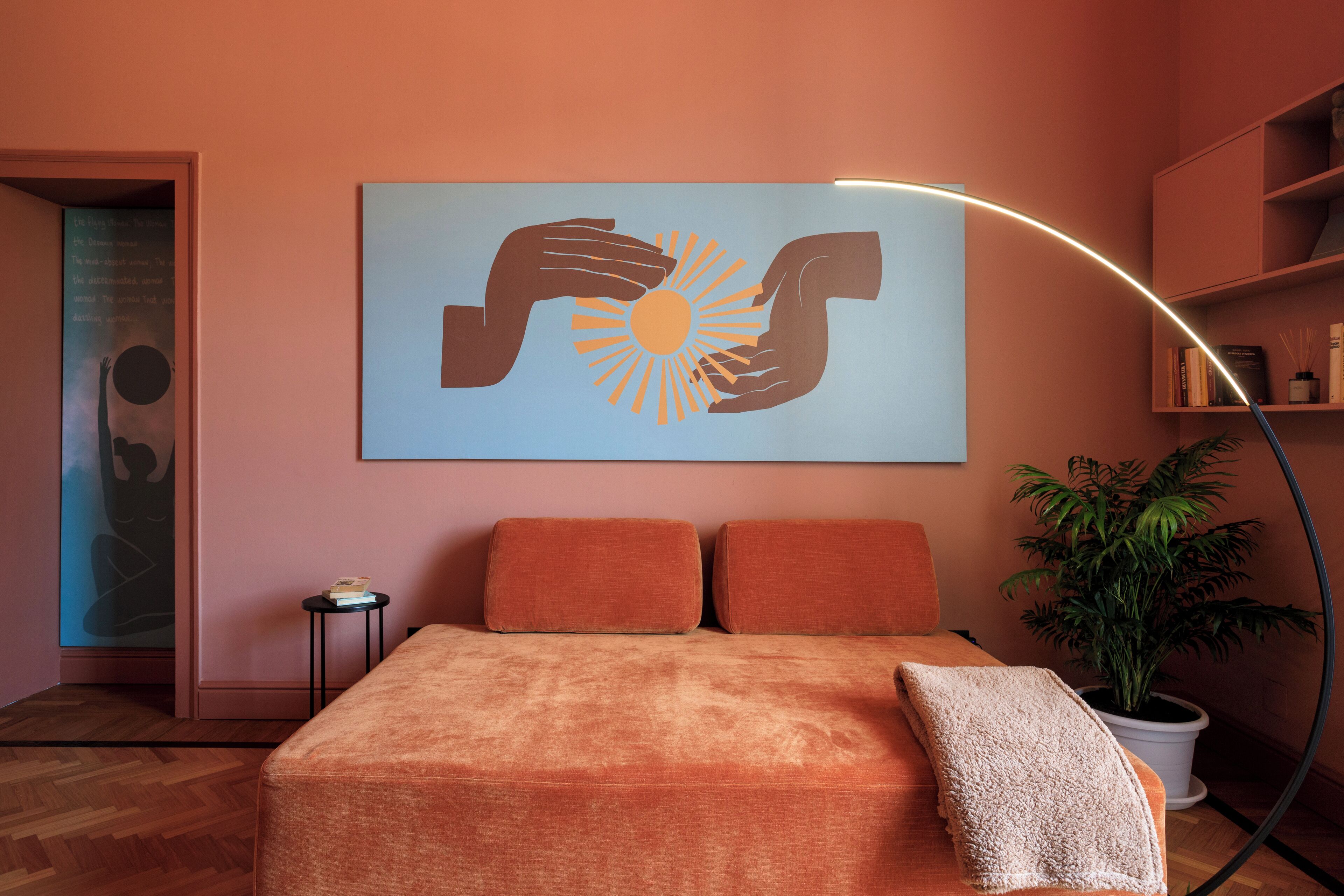Ein Schlafzimmer mit Bett, zwei Kissen, einem Nachttisch, einem Wandbild, einer Topfpflanze und einem Bücherregal.