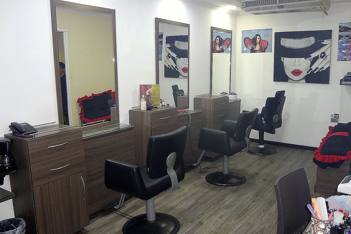 A salon with wooden cabinets, multiple mirrors, and black salon chairs.