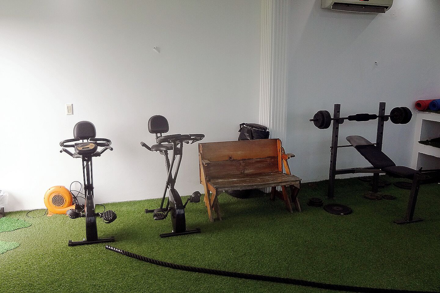 A gym with exercise equipment, a bench, and a small table.