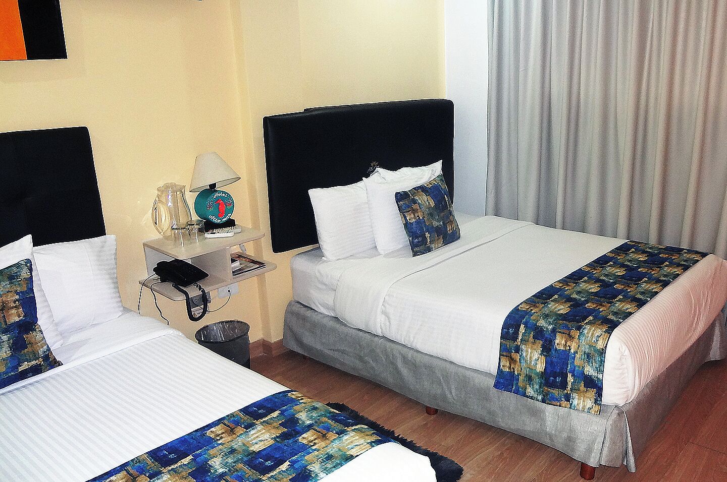 Een hotelkamer met twee bedden, een nachtkastje, een lamp en een wereldbol.