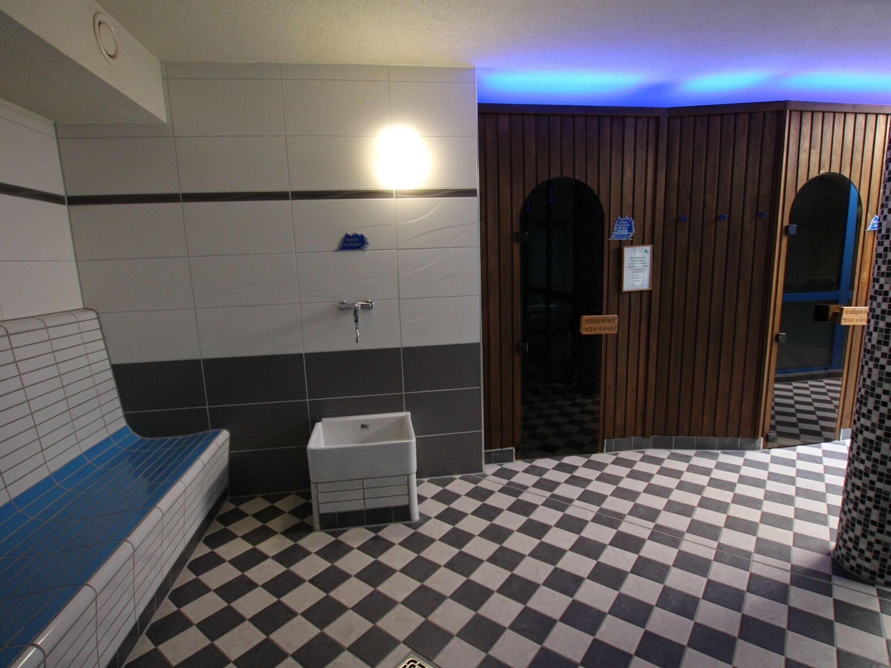 A bathroom with a checkered floor, a sink, and a bench.