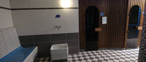 A bathroom with a checkered floor, a sink, and a bench.
